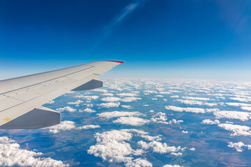 Obraz premium View from the airplane window at a beautiful cloudy sky and the airplane wing