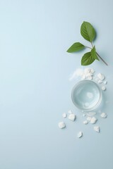 Top view of glass water cup with ice cubes and green leaves on light blue background, symbolizing freshness, hydration, purity, and clean natural wellness concept for health, spa, and eco-friendly des