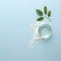 Top view of glass water cup with ice cubes and green leaves on light blue background, symbolizing freshness, hydration, purity, and clean natural wellness concept for health, spa, and eco-friendly des