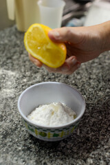 Squeezing Lemon Juice into Powdered Sugar on Speckled Countertop