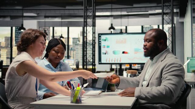 HR staff members speak with job seeker during interview in corporate office, analyzing resume and application for the organization work culture. Hiring process for talent acquisition. Camera A.