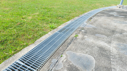 Steel grating covering a roadside drainage channel, creating a flat and even surface for safety, ensuring durability,