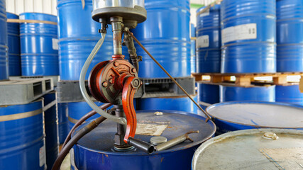 Hand-operated rotary oil pump attached to a 200-liter oil barrel inside a storage facility,