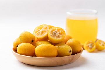 Fresh kumquats fruit and juice on white background