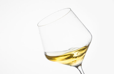 Glass of white wine tilted against a clean white background, minimal and elegant composition.