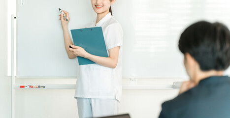 Obraz premium Female staff including nurses, pharmacists, and registered dietitians explaining in front of a whiteboard at a medical conference 