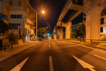 オレンジ色の街灯が明るい深夜のモノレールのレールと道路