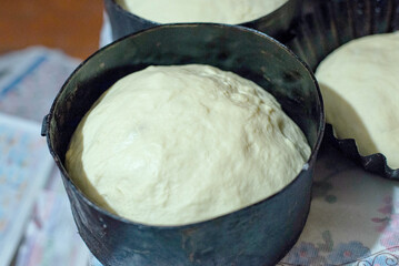 Raw yeast dough in black baking molds close up