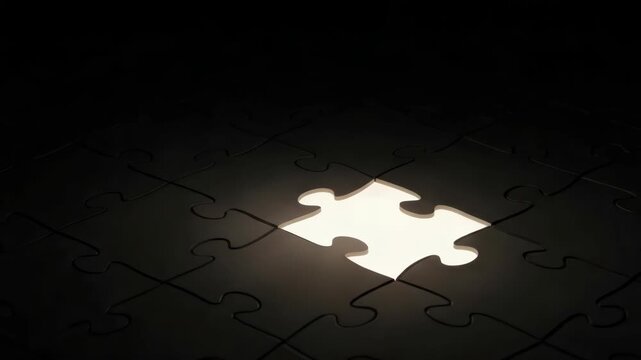 array of dark puzzle pieces on deep black surface with one central piece missing A brilliant warm white light emanates from the empty space illuminating the surrounding dark edges