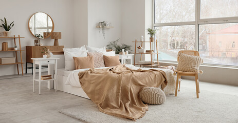 Stylish interior of bedroom with comfortable bed and chair with cushion