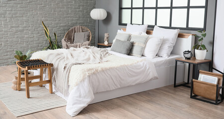 Interior of bedroom with big bed, armchair and tables