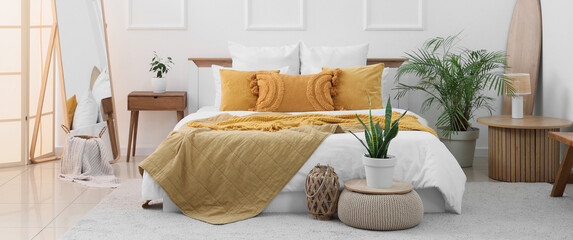 Interior of light bedroom with big bed, mirror and tables