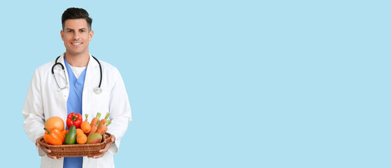 Male doctor holding basket with healthy food on blue background