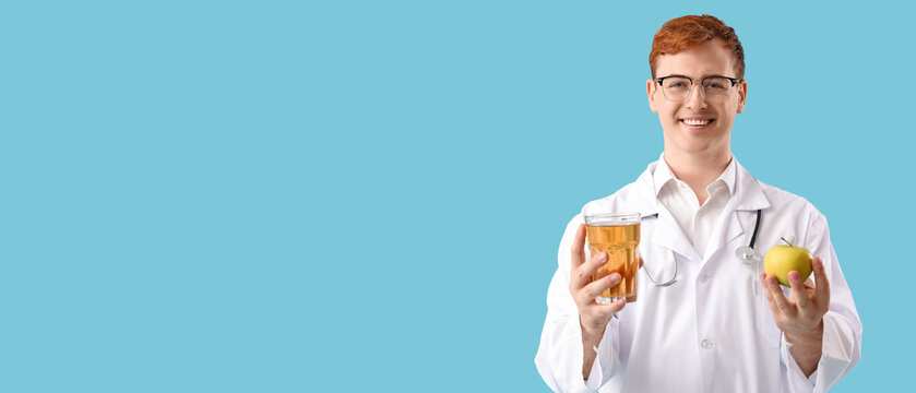 Male doctor with glass of juice and apple on blue background
