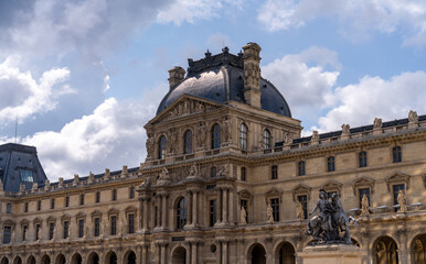 The Louvre Museum in Paris under a cloudy sky.