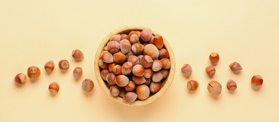 Bowl with shelled hazelnuts on beige background