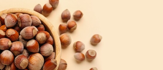 Bowl of tasty hazelnuts on beige background with space for text, closeup