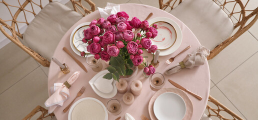 Beautiful table setting with pink roses and candles for wedding celebration in room, top view