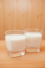Two glasses of fresh white milk on the table on the kitchen, vertical card of drink