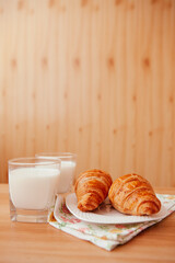 Glasses of milk and croissants on the table on the kitchen, vertical card with copy space