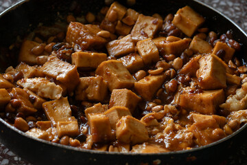 A close-up of Vietnamese braised tofu with peanuts in a pan, a delicious and savory vegetarian dish from Asian cuisine