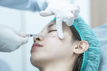Beautician doctor making filler injection to woman under eye,  asian lady  getting filler treatment.