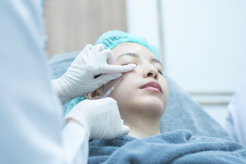 Naklejka premium Beautician doctor making filler injection to woman under eye, asian lady getting filler treatment.