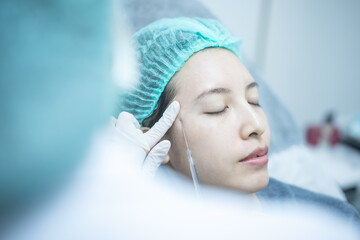Beautician doctor making filler injection to woman under eye,  asian lady  getting filler treatment.