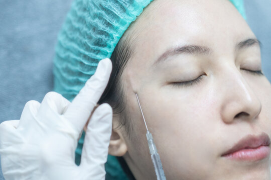 Beautician doctor making filler injection to woman under eye,  asian lady  getting filler treatment.