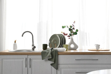 Clean towel and many dishes on counter near sink in kitchen
