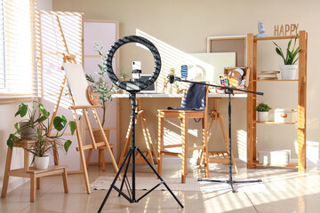 Interior of blogger's office with workplace, laptop, lamp and microphone on wooden table