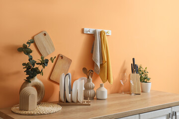 Clean towels hanging on orange wall and many dishes at counter in kitchen