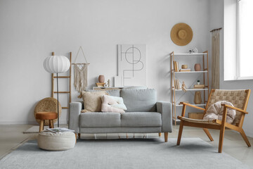 Interior of stylish living room with grey sofa, shelving unit and armchair