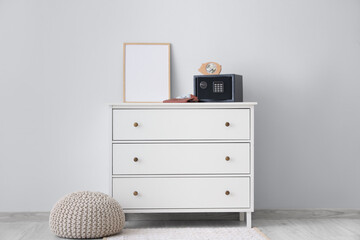 Modern safe box with piggy bank, money in wallet and painting on commode near white wall