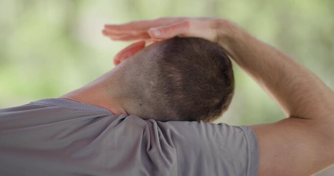 Demonstration of neck stretching technique for improved flexibility and relaxation in outdoor setting
