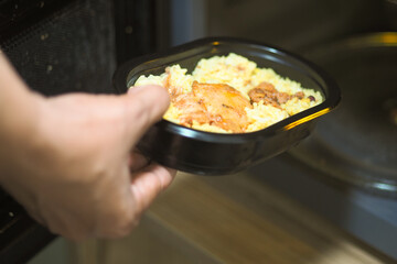 Hand reaches for warm meal from microwave