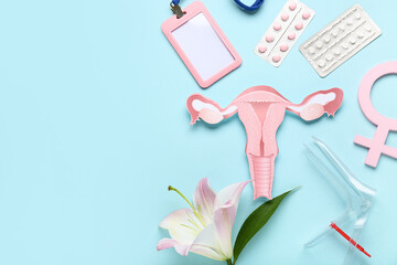 Gynecological speculum with symbol of woman, paper uterus, badge, lily flower and different pills on blue background