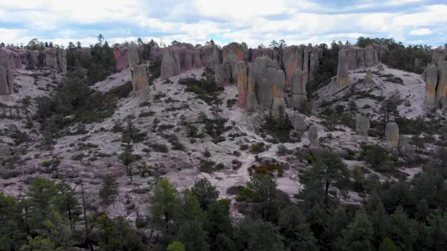 zoom in con dron sobre el valle de los monjes en el estado de chihuahua, formaciones rocosas y monolitos de piedra rodeados de un bosque verde