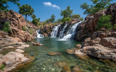 Fototapeta premium Waterfall cascading into a crystal-clear pool. Lush foliage surrounds the rocky falls