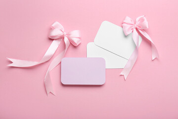 Composition with blank cards and silk bows on pink background, closeup