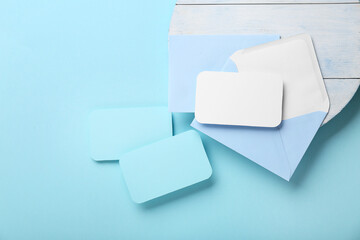 White wooden tray, paper envelope and blank cards on blue background, closeup