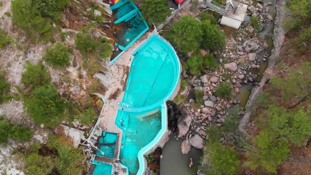 Toma cenital con dron de las aguas termales de Recowata chihuahua, a lado un arroyo, albercas azules con agua cristalina