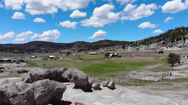 Majestuoso paisaje monta&ntilde;oso con picos rocosos, un valle verde y un cielo azul con nubes blancas en un d&iacute;a de verano en la sierra de chihuahua M&eacute;xico