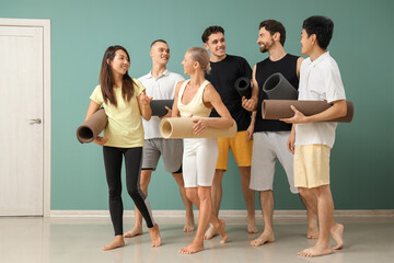 Naklejka premium Group of sporty young people with yoga mats near green wall