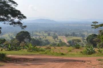 A scenic view of rolling hills and valleys, with a dirt road leading into a lush landscape filled with trees and greenery under a clear sky.