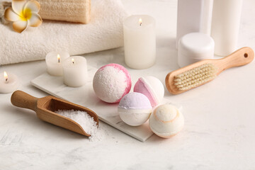 Composition with tray, bath bombs and scoop with sea salt on white grunge background, closeup