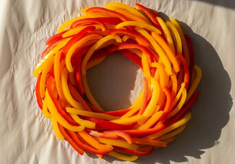 Bell pepper loops woven into a bold wreath on off‑white fabric, circular vegetable motif for healthy recipe visuals, culinary branding and cooking magazine design