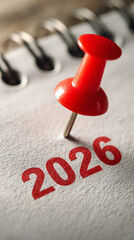 Close-up view of a red pushpin marking the year 2026 on a notebook