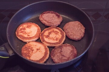 Tasty chicken cutlets and beef patties sizzling in frying pan on stove. Homemade cooking process, fresh meal preparation, traditional protein food, kitchen concept with fried meat.