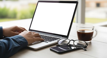 Focused professional types on a modern laptop with coffee and glasses, working productively in a bright, airy workspace with natural light streaming in.